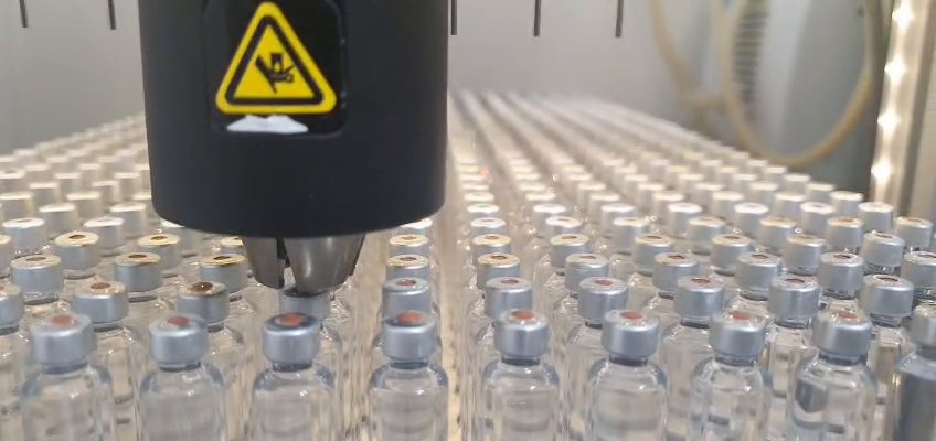 The PleniDose Gantry head low over the cartridge mouths during aliquoting — the metered, unhurried delivery the platform is built around